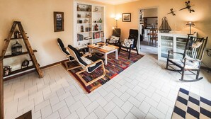 A cozy living room with a bookshelf, a ladder, a dining area with chairs, and a kitchen visible in the background. - 4 bedroom stunning home in Béziers (Béziers)