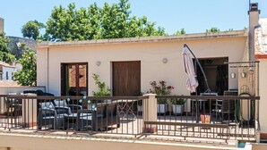 A balcony with a metal railing, a table with chairs, and a potted plant. - 4 bedroom stunning home in Béziers (Béziers)