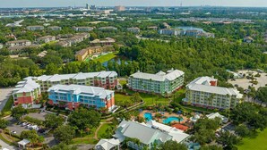 A multi-story hotel with a swimming pool, surrounded by greenery and other buildings. - Worldmark Orlando Kingstown Reef Studio Deluxe (Orlando)