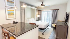 A hotel room with a bed, a desk with a telephone, a chair, a television, and a ceiling fan. - Worldmark Orlando Kingstown Reef Studio Deluxe (Orlando)