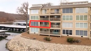 Un hotel de varios pisos con vista al río, mobiliario exterior y un muelle con barcos.