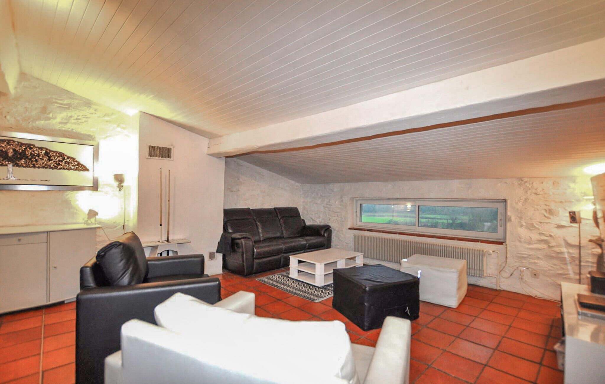 A living room with a black leather sofa, white armchairs, a coffee table, and a view of a green landscape through a window.