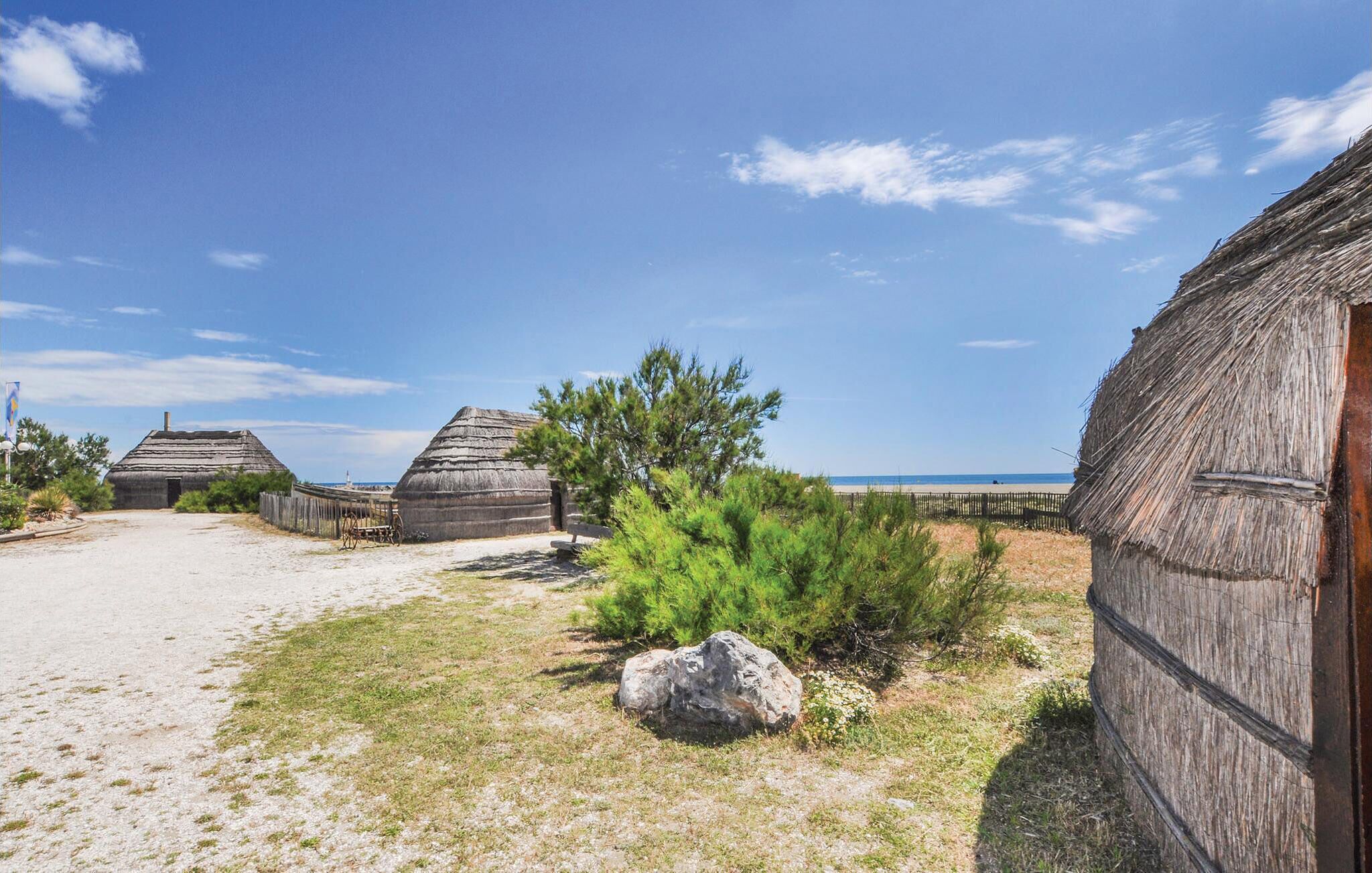 A coastal village with traditional thatched-roof houses, a sandy path, and a clear blue sky.