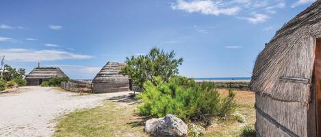 A coastal village with traditional thatched-roof houses, a sandy path, and a clear blue sky.