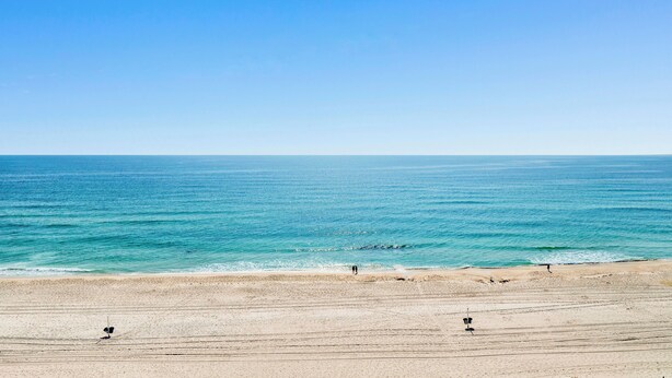 A beach with a clear sky, calm sea, and a sandy shore. - Pet Friendly! Beach Front- East Corner Unit- 2 Pools- Caribbean 501 (Gulf Shores)