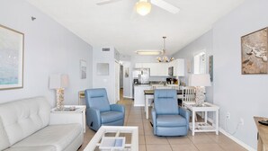 A modern living room with a white sofa, two blue armchairs, a coffee table, and a ceiling fan. - Pet Friendly! Beach Front- East Corner Unit- 2 Pools- Caribbean 501 (Gulf Shores)