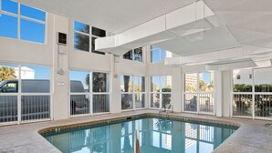 An indoor swimming pool with clear glass walls, a pool ladder, and a view of the outside. - Pet Friendly! Beach Front- East Corner Unit- 2 Pools- Caribbean 501 (Gulf Shores)