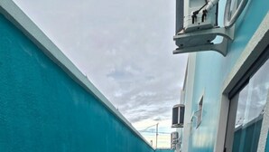Un couloir aux murs de couleur turquoise et au sol carrelé, qui mène à une porte au fond.