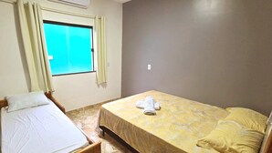 Une chambre avec deux lits, une fenêtre et un climatiseur fixé au mur.