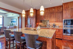 Una cucina moderna con mobili in legno, un piano di lavoro in granito ed elettrodomestici in acciaio inossidabile.