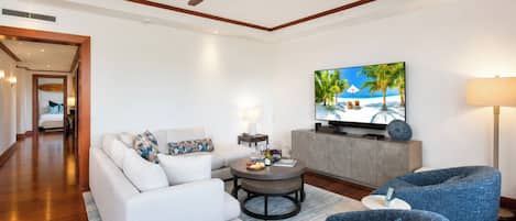 Uma sala de estar moderna com sofá, poltronas, mesa de centro, televisão e ventoinha no teto.