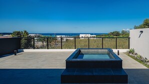 Une terrasse sur le toit avec une piscine, une vue sur l’océan et un ciel dégagé.