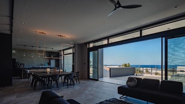 Un intérieur moderne comprenant un coin repas, une cuisine et un balcon avec vue sur la mer.