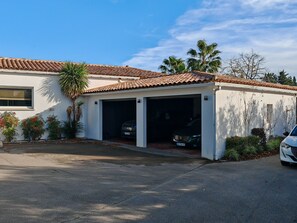A single-story house with a garage, a tiled roof, and a palm tree. - The atrium house - Swimming pool & spa (Saint-Aunès)