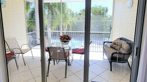 A glass door leading to a balcony with a table, chairs, and a wicker sofa. - !Fun for Families! Large Pool Home + Game Room! (Fort Myers Beach)