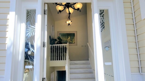 A staircase leading to a second floor with a painting on the wall and a chandelier above. - !Fun for Families! Large Pool Home + Game Room! (Fort Myers Beach)