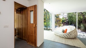 A modern interior with a wooden door, a white wall, and a view of a garden through large windows. - The Art House by the Beach (Brighton)