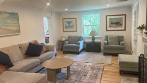 Ein Wohnzimmer mit einer Couch, zwei Sesseln, einem Couchtisch, einem Teppich und einem Kamin.