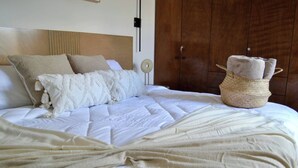 A neatly made bed with a white comforter and a beige throw blanket. - Encanto Department We Bill (San Miguel de Allende)