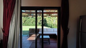 Ein Zimmer mit einer Schiebetür, die auf eine Terrasse mit einer Couch und einem Tisch führt.