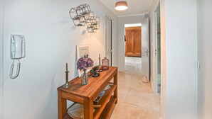 Un corridoio con un tavolino consolle in legno, un telefono a parete, un quadro incorniciato e una porta che dà su un'altra stanza.