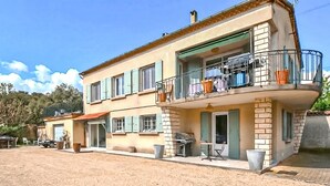 Un edificio di due piani con un balcone, un'area barbecue e un piccolo spazio salotto all'aperto.