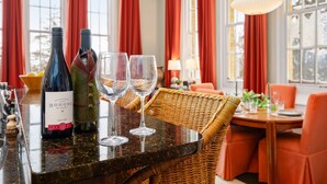 Zona pranzo con tavolo apparecchiato per due, una bottiglia di vino e due bicchieri.