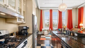 Cucina con piano cottura a gas, frigorifero, macchina da caffè e pavimento a scacchi.