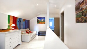 En modern inredning med en vit soffa, en färgstark, abstrakt målning och en minimalistisk design.