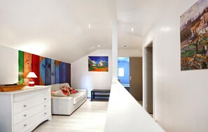 Ein modernes Interieur mit einem weißen Sofa, einem farbenfrohen abstrakten Gemälde und einem minimalistischen Design.