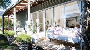 A modern outdoor seating area with a sofa and chairs, surrounded by potted plants and a wooden deck.
