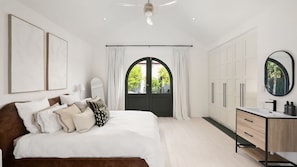 A bedroom with a bed, a dresser, a mirror, and a door with a view.