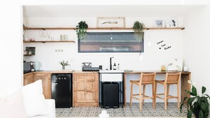 Een moderne keuken met houten kastjes, een zwarte vaatwasser, een spoelbak en een bar voorzien van twee houten krukken.