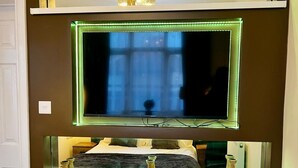 A television mounted on a wall with a shelf below it. - Beautiful 2-bedroom apartment near LHR (Feltham)