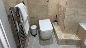 Kylpyhuone, jossa on wc, pyyheteline, wc-paperiteline ja suihkutila.