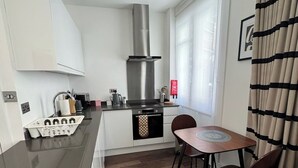 Moderni keittiö, jossa on liesi, uuni ja ruokailutila, jossa on pöytä ja tuolit.