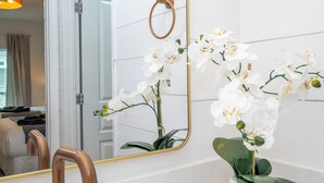 Ein Badezimmer mit Spiegel, Handtuchhalter und weißen Orchideen.