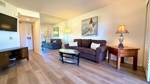 A modern living room with a sofa, coffee table, TV, and lamp. - Easy Access Lower Unit + Golf Views + Festival Location (La Quinta)