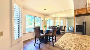 A modern kitchen with a dining area, large windows, and a refrigerator. - Easy Access Lower Unit + Golf Views + Festival Location (La Quinta)