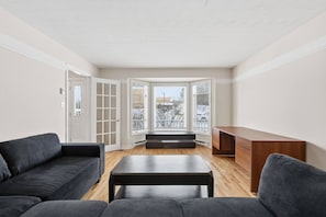 A living room with a sofa, a coffee table, and a wooden cabinet. - Executive 7 Bedrooms 3 5 Bathrooms (Bedford)