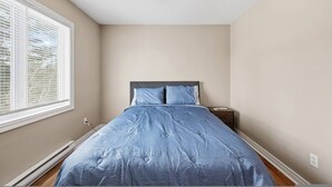 A bedroom with a bed, a nightstand, a ceiling fan, and a window with blinds. - Executive 7 Bedrooms 3 5 Bathrooms (Bedford)
