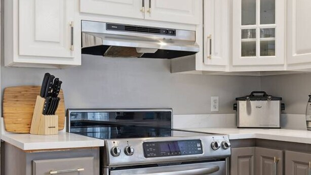 A kitchen with white cabinetry, a built-in oven, a stovetop, and a toaster. - Executive 7 Bedrooms 3 5 Bathrooms (Bedford)