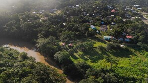 Vista aerea di una zona rurale con case sparse, un fiume e vegetazione fitta.