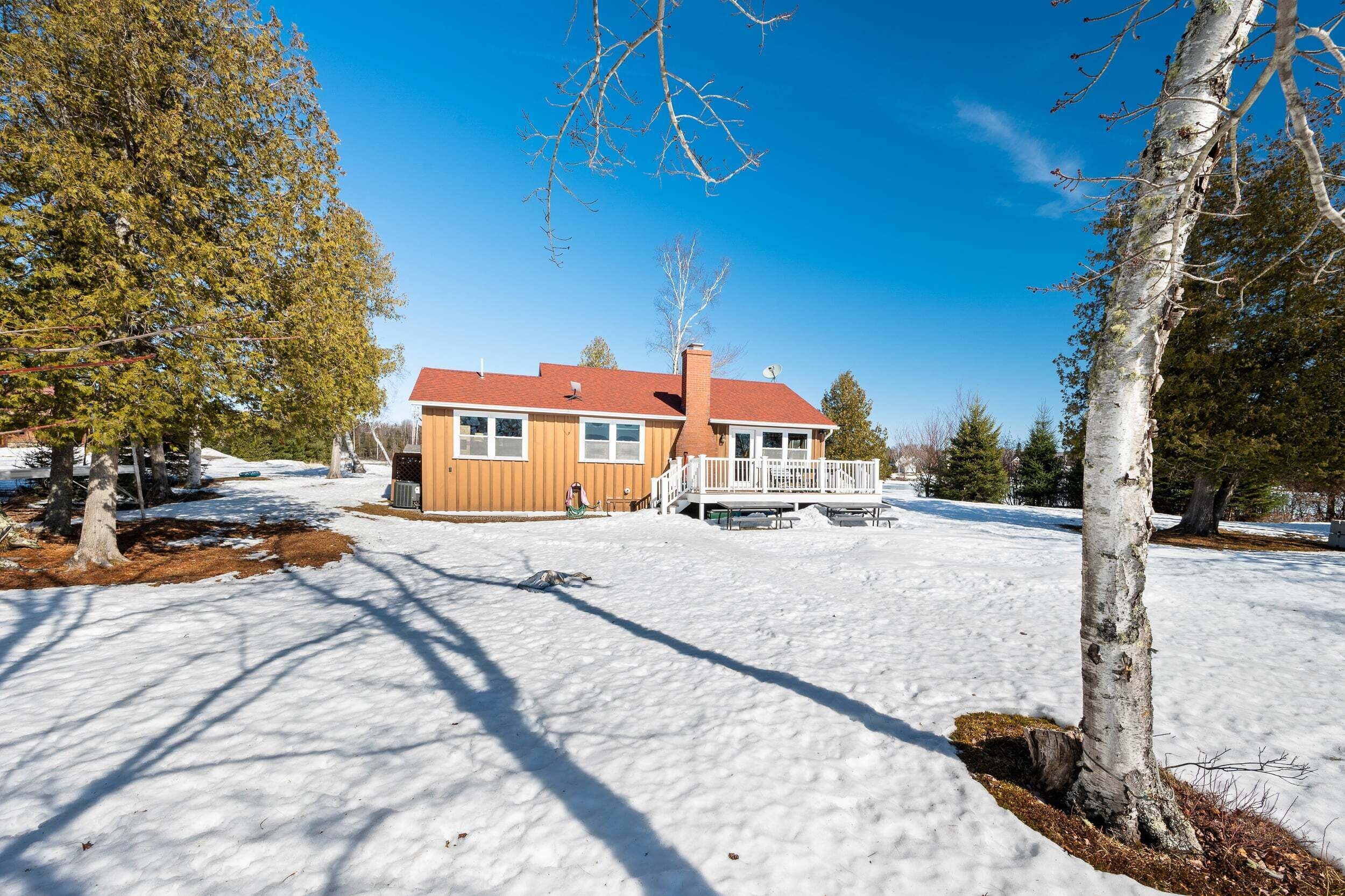 A house with a red roof, a wooden deck, and a snow-covered yard.