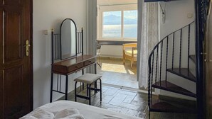 A bedroom with a bed, a dresser, a mirror, a chair, a staircase, and a view of the sea. - 1 bedroom amazing apartment in Nafpaktos (Nafpaktos)