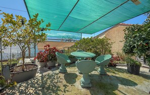 Une terrasse extérieure avec une table et des chaises, entourée de plantes en pot et offrant une vue sur la mer.