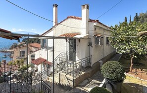 Un bâtiment situé sur la côte, doté d’un toit recouvert de tuiles rouges, d’un balcon et d’un escalier menant à l’entrée.