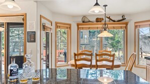 Cocina con encimera de granito, sillas de madera y lámpara colgante.