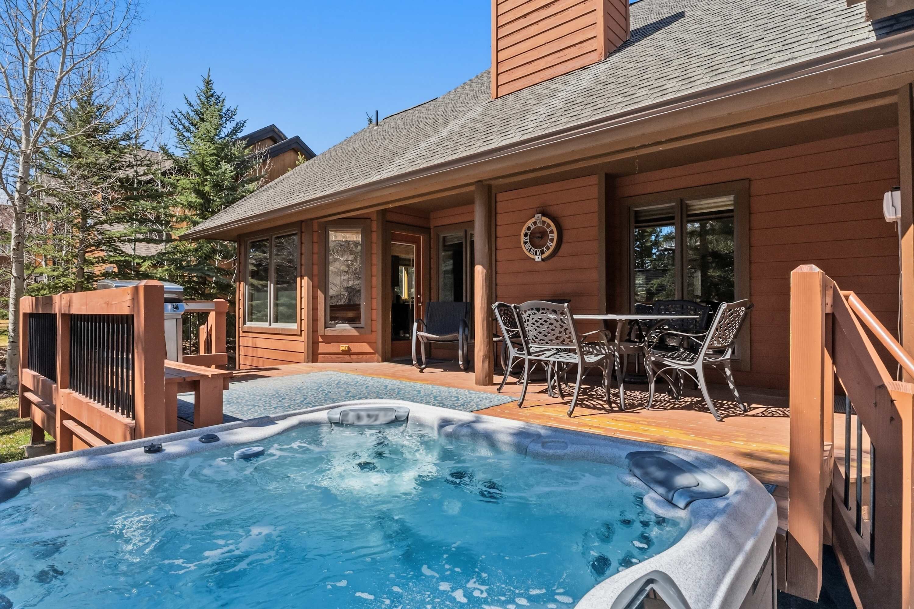 A wooden house with a hot tub, outdoor seating, and a clock on the wall.