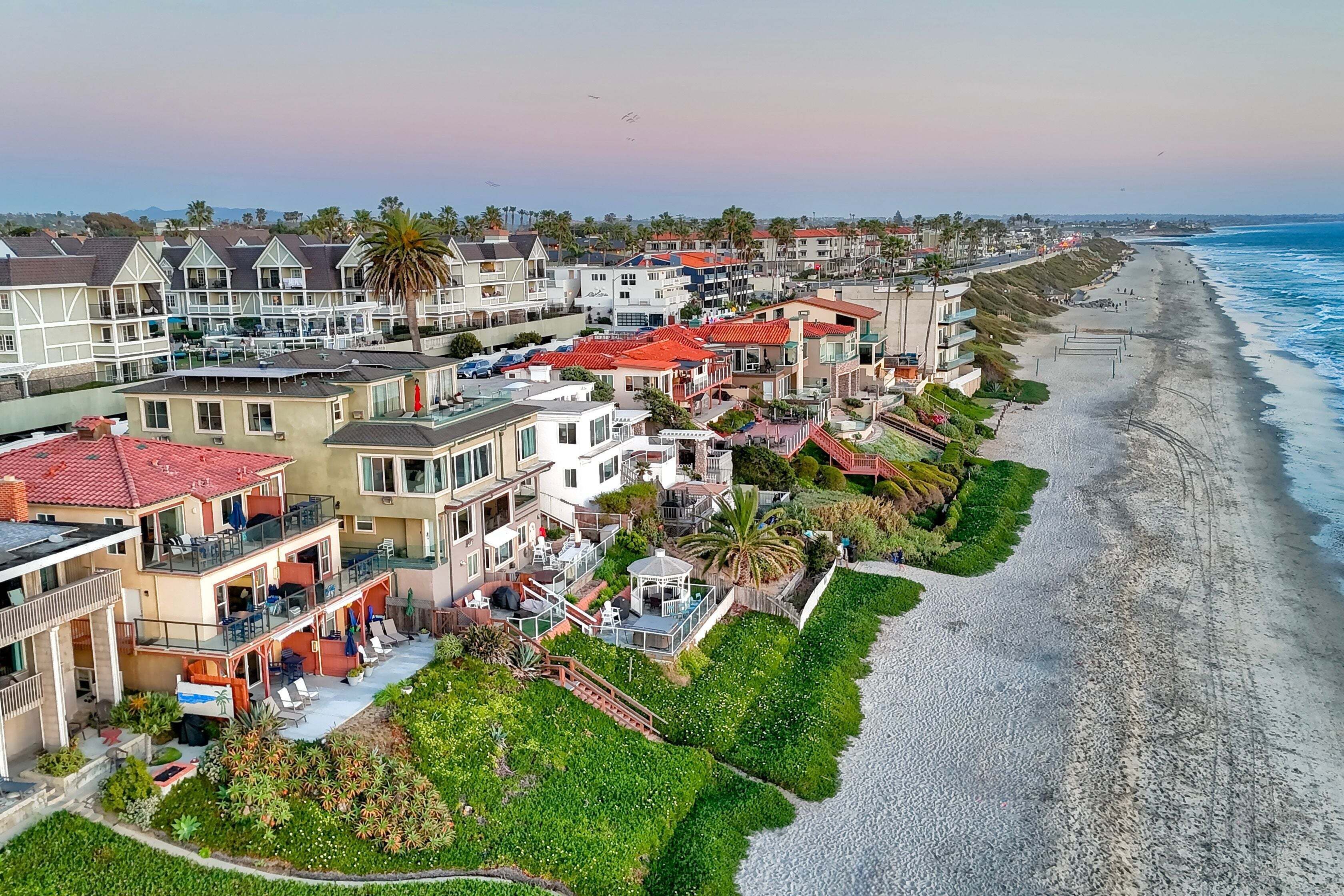 Une zone résidentielle côtière avec des maisons, une plage et un ciel dégagé.